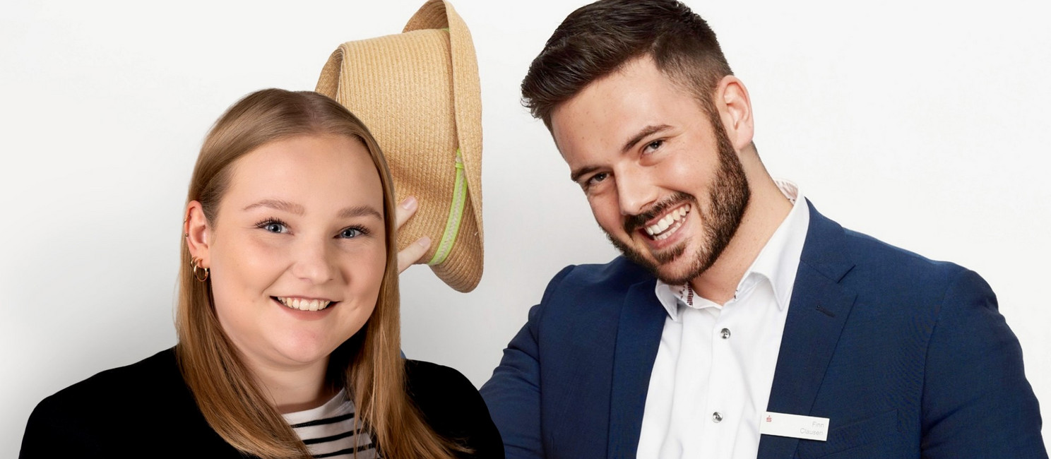 Foto von Monique Kraak und Finn Clausen vor einer weißen Wand. Sie lächeln beide, tragen Anzug und Blazer und Finn hat seinen Hut zum Gruß in der Hand.