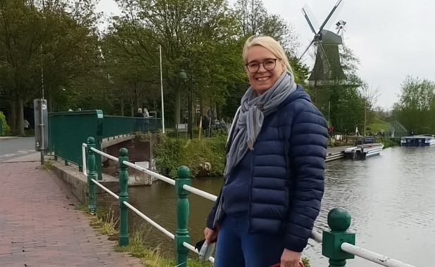 Imke Conrad auf einer Brücke an einem Fluss. Im Hintergrund steht eine große Mühle.