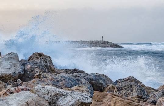 Gischt  schlägt gegen Felsen am Ufer
