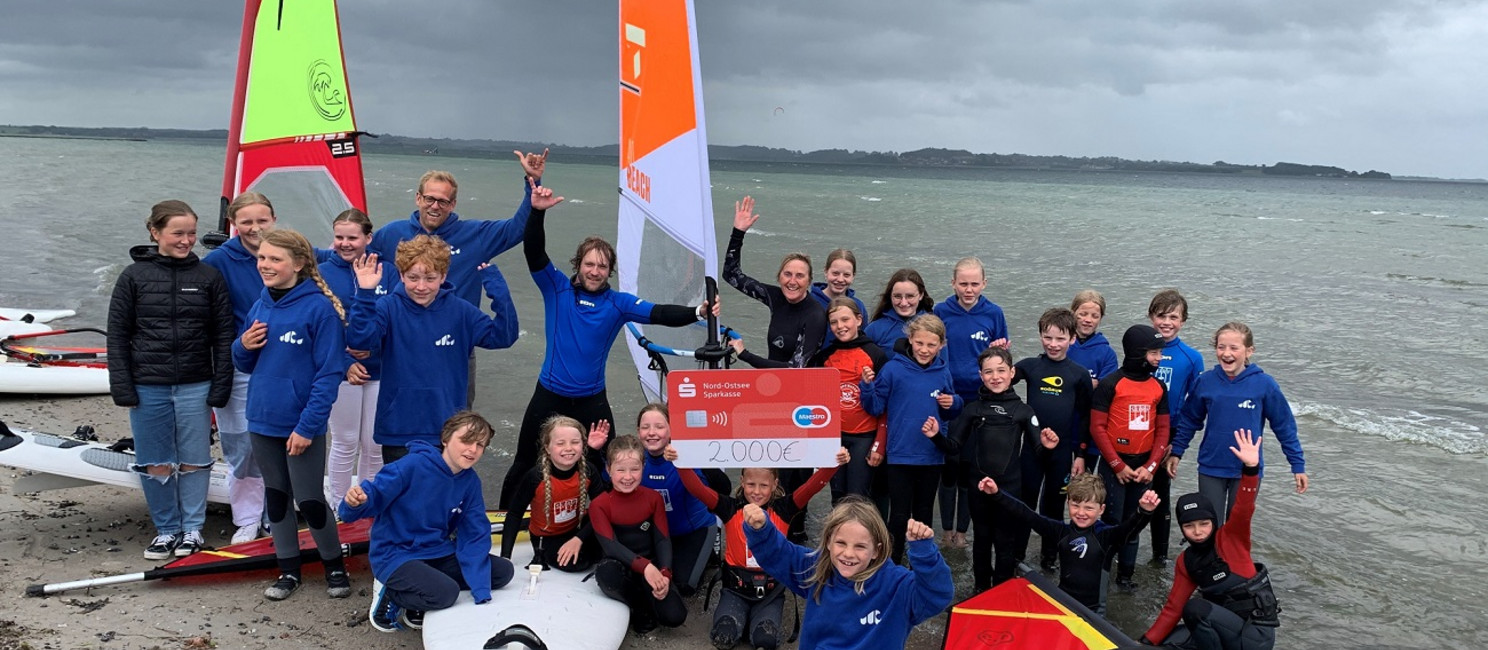 Jubelnde Kinder mit Surfbrettern am Strand