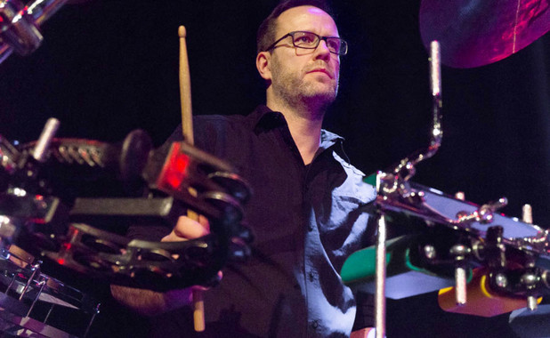 Lars Hansen auf einer Bühne mit einem Drumstick in der Hand an seinen Percussions.