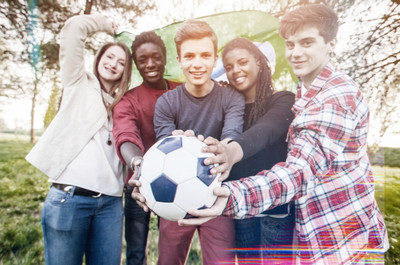 Gruppe von Jugendlicher halten einen Fußball in die Kamera.